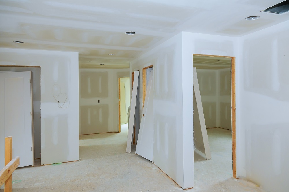 The image shows a room under construction with bare walls and floors, and there are visible studs and insulation materials in progress.