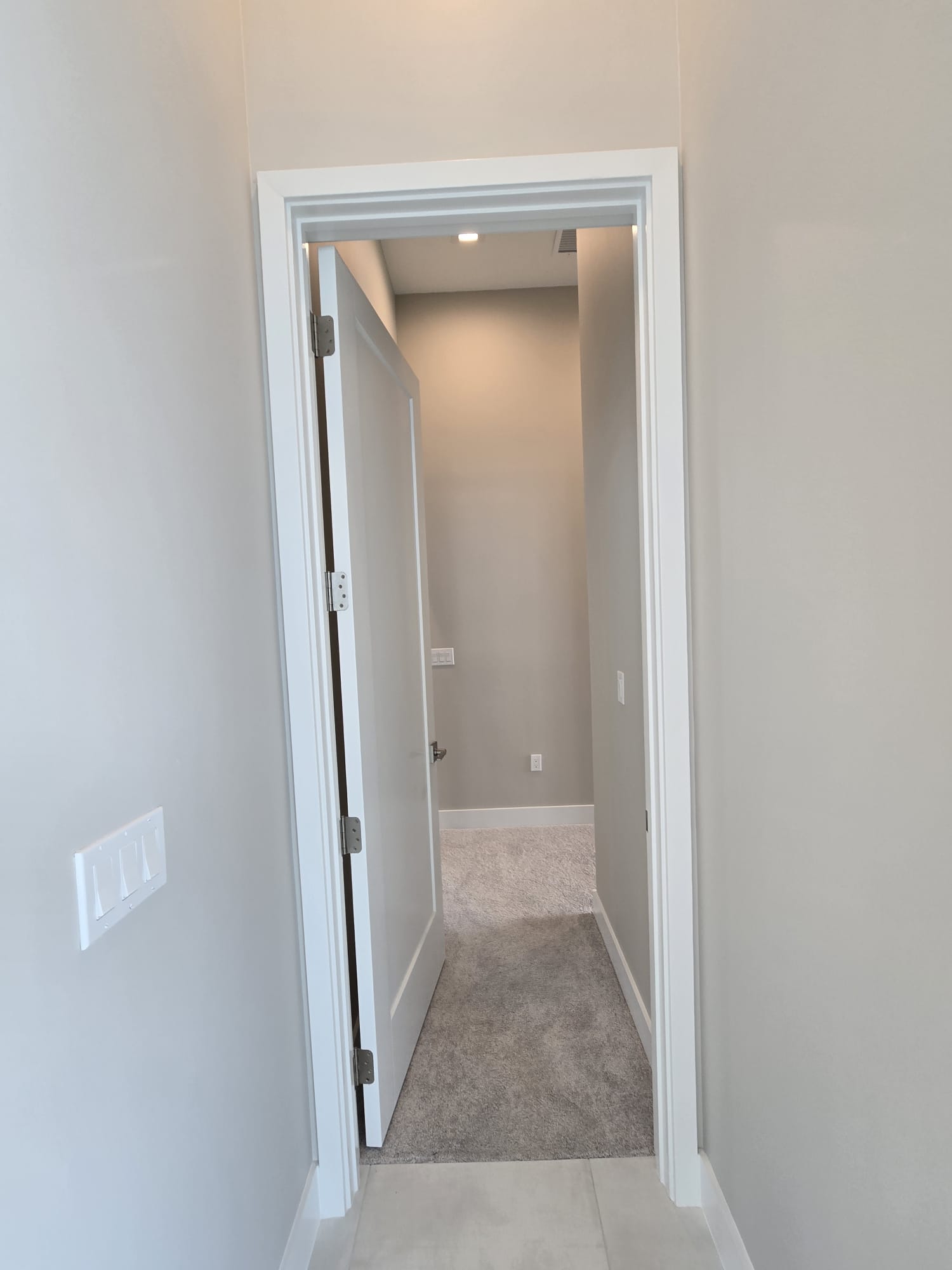 The image shows an interior view of a hallway leading into a room with tiled walls and a white door frame.