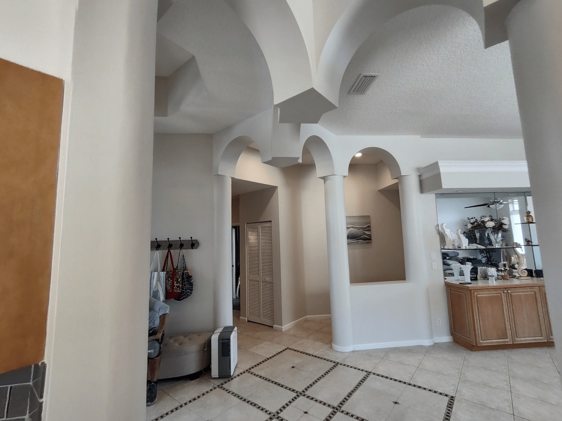 This image depicts an interior view of a spacious room with high ceilings, arched doorways, and architectural features, which appears to be a lobby or entrance area within a residential building.