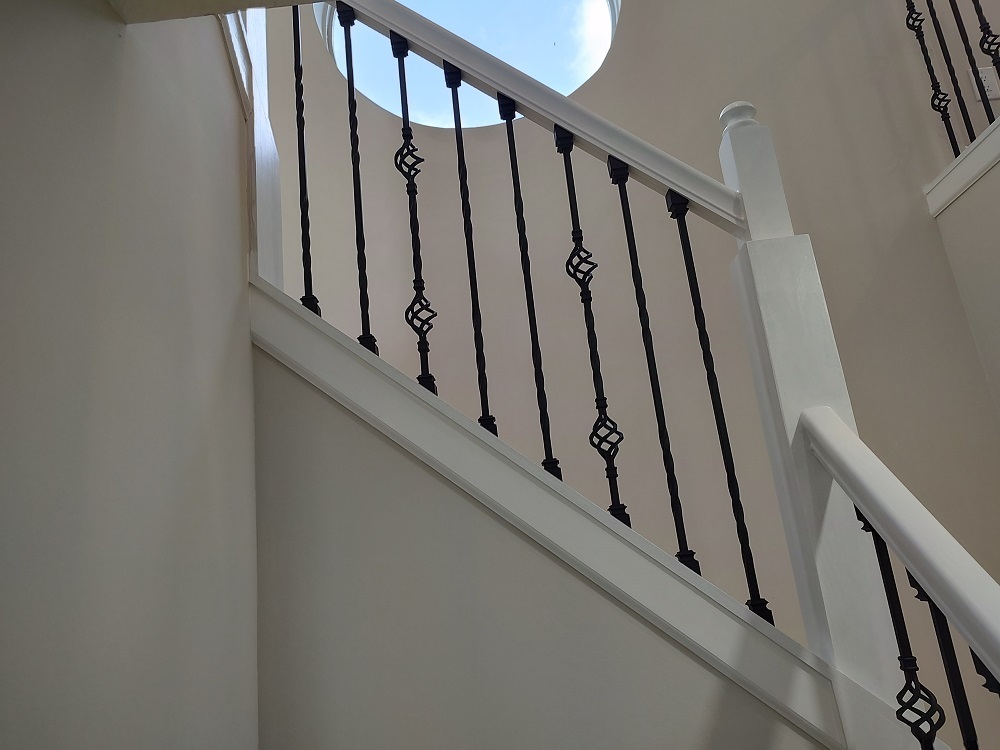 The image shows a staircase with a black railing and white steps, leading up to a doorway at the top.