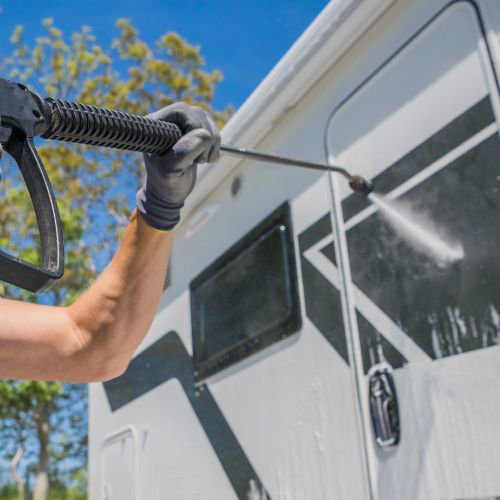 A man is cleaning a camper van using a pressure washer.