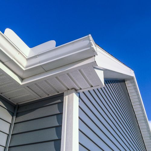 The image displays two identical views of a building facade with a gabled roof and white siding, showcasing a close-up view of a white horizontal blind installed over a window.